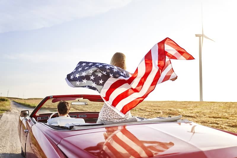 Woman holding an American flag on a road trip-cm